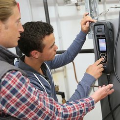 Zwei Anlagenmechaniker die mit einem Klimamessgerät eine Heizung prüfen