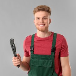 EIn junger Anlagenmechaniker mit einer Rohrzange in der Hand