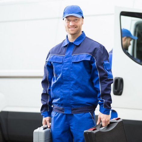 Ein Monteur steht mit zwei Werkzeugkoffer in den Händen vor einem Bulli