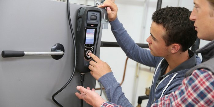 Ein junger Anlagenmechaniker bedient ein Messgerät