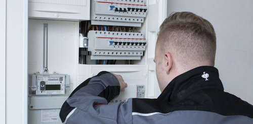 Ein Elektroniker der an einem Verteilerkasten arbeitet