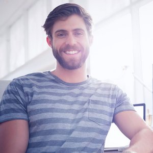 Ein Mann der an seinem Bürotisch sitzt und eine Fensterfront hat